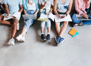 retrato-arriba-jovenes-portatiles-telefonos-inteligentes-sentados-juntos-suelo-estudiantes-escribiendo-conferencias-sosteniendo-libros-texto-rodillas.jpg